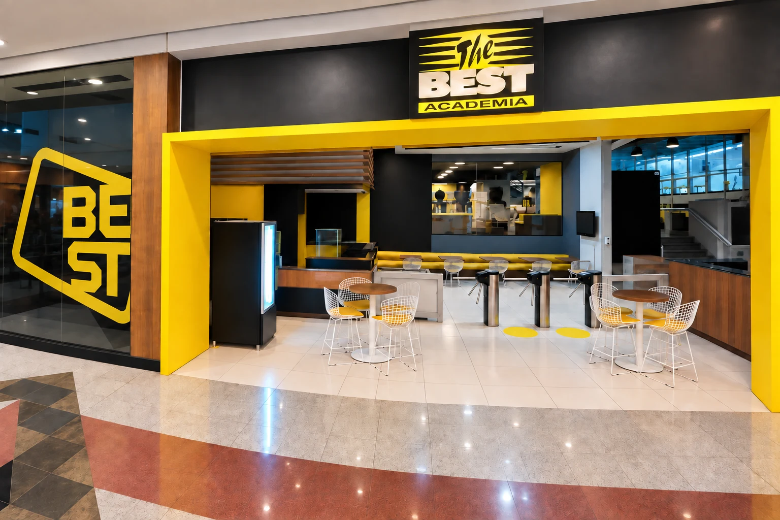 Prévia da entrada da The Best vista pelo corredor do Shopping Mueller, com portal amarelo e letreiro da academia