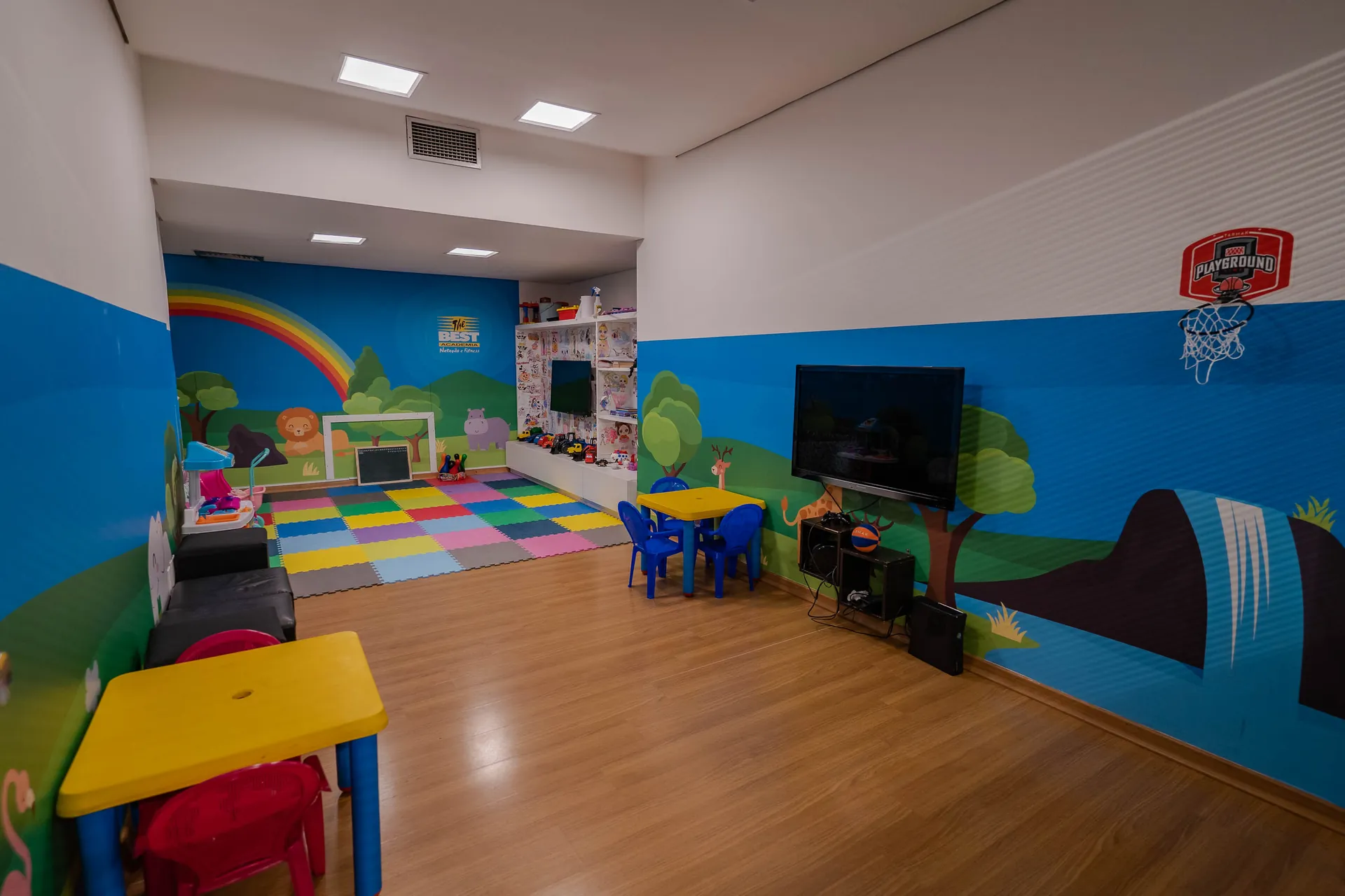 Espaço infantil colorido com tatame, mesas e brinquedos