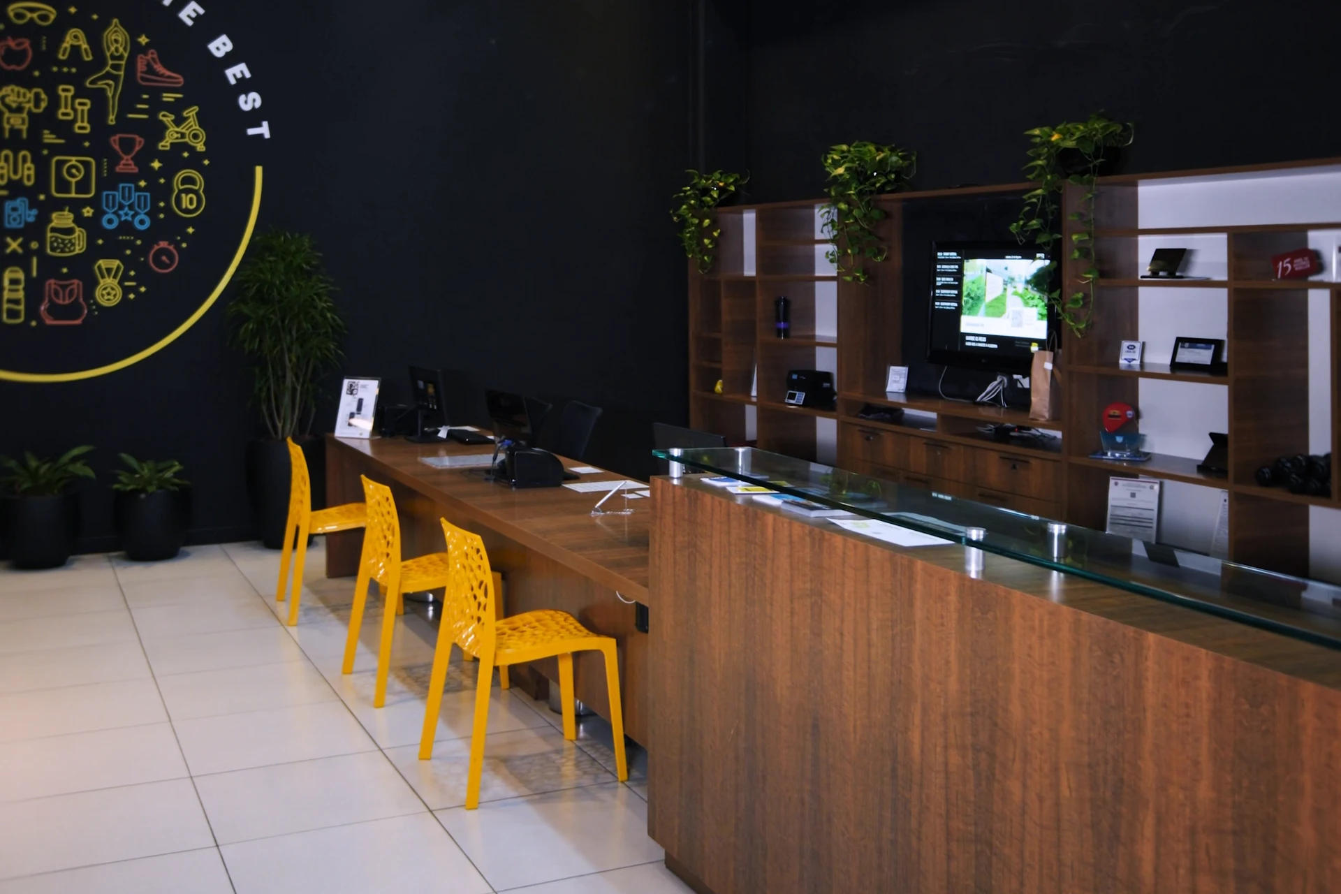 Recepção da The Best, com balcão de madeira e cadeiras amarelas