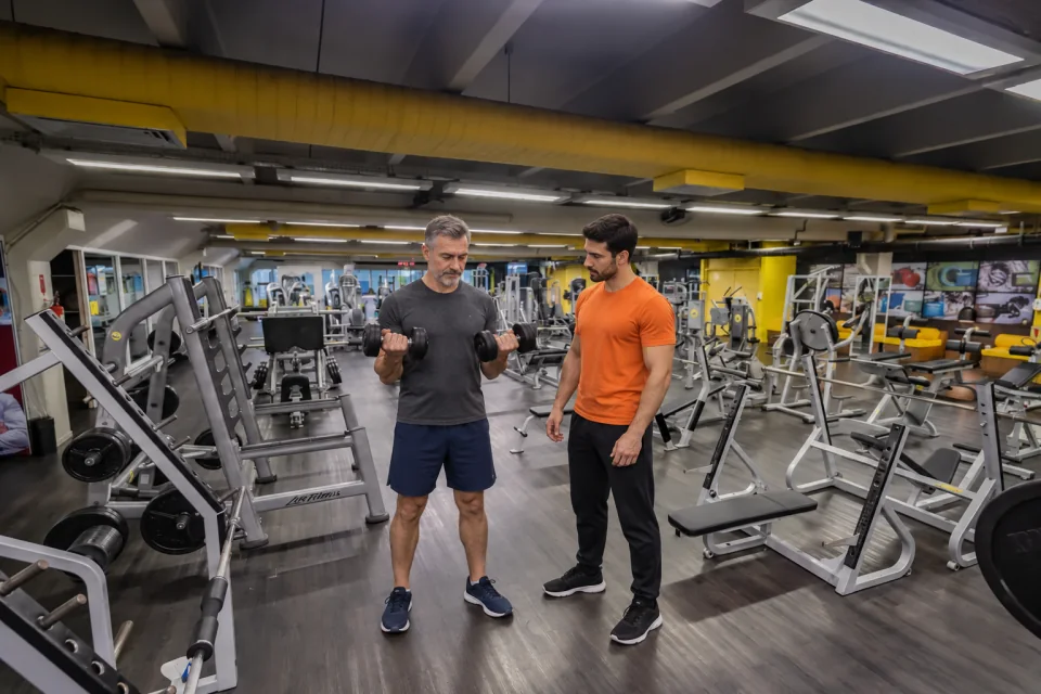 Pessoas treinando com pesos livres na sala de musculação da The Best